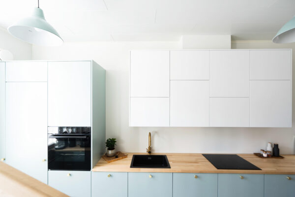 Maalattujen mdf-ovien vakiosävyissä on paljon herkullisia vaihtoehtoja, kuten tämän keittiön raikas Opaali. Maalattuja ovia voit tilata meiltä myös omalla sävyllä. Tässä kaksivärisessä keittiössä yläkaapisto on valkoinen. Lämpöä kokonaisuuteen tuovat massiivipuiset tasot.