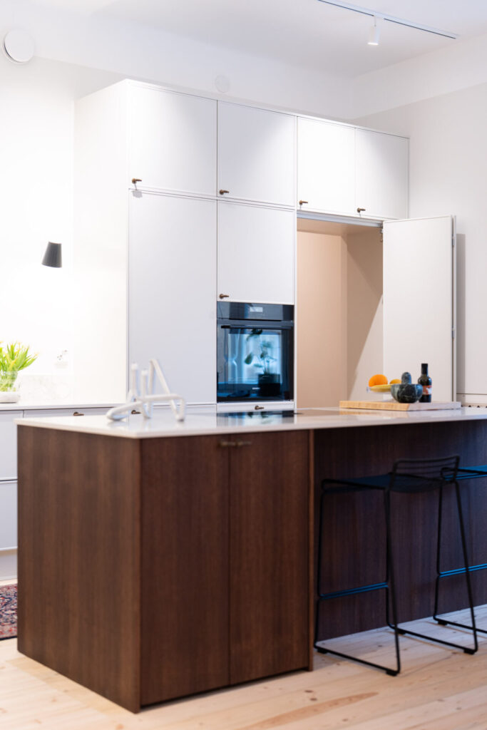 Kaksivärisessä keittiössä ruokakomeron kulkuovi naamioituu komeroseinään.