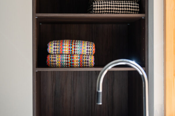 Kalustukseen istutettu hyllykkö tuo viimeistellyn tunnelman kodinhoitotilaan ja tarjoaa säilytyspaikan esimerkiksi pyyheliinoille.